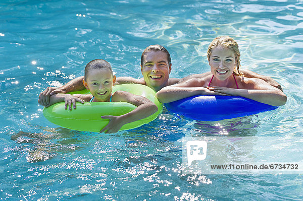 Girl (10-11) with parents in swimming pool