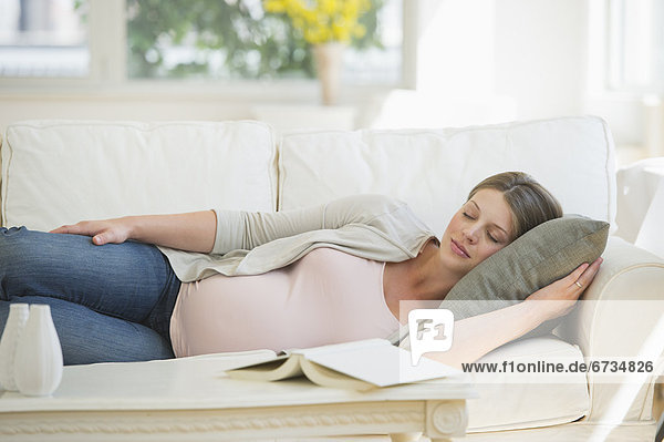 Junge schwangere Frau schlafen auf sofa