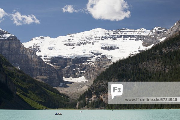 'Mount Victoria And Lake Louise With Canoes In The Distance And Blue Sky With Clouds