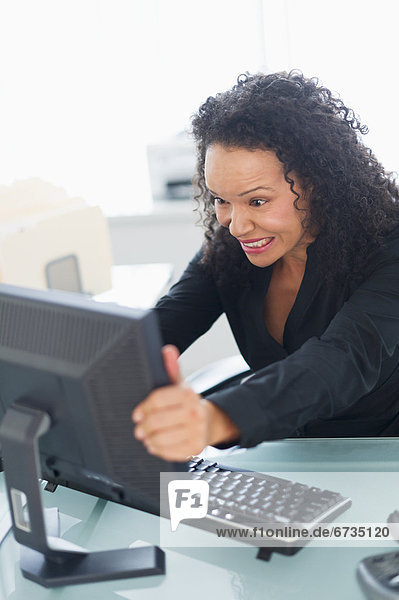 Business woman shaking computer monitor