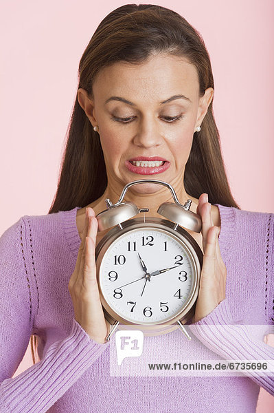 Studio shot of woman holding alarm clock