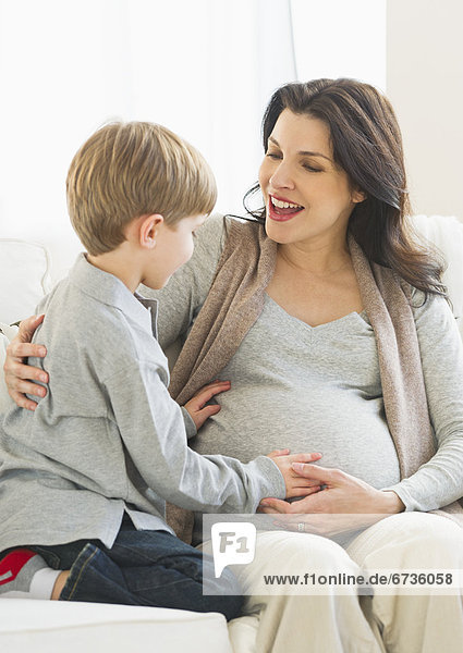 Boy (4-5) touching pregnant mother's belly