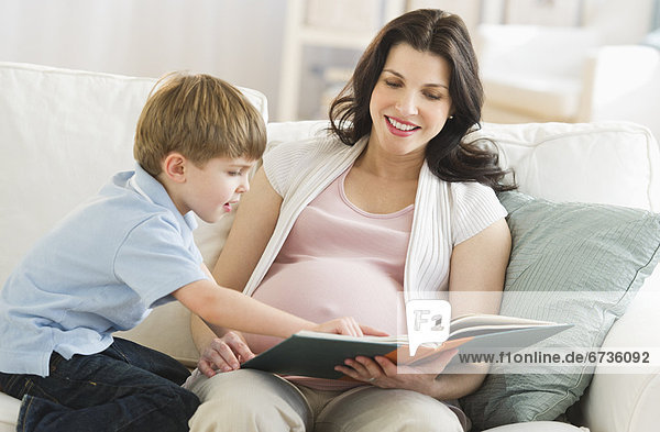 Mother and son (4-5) reading book on sofa