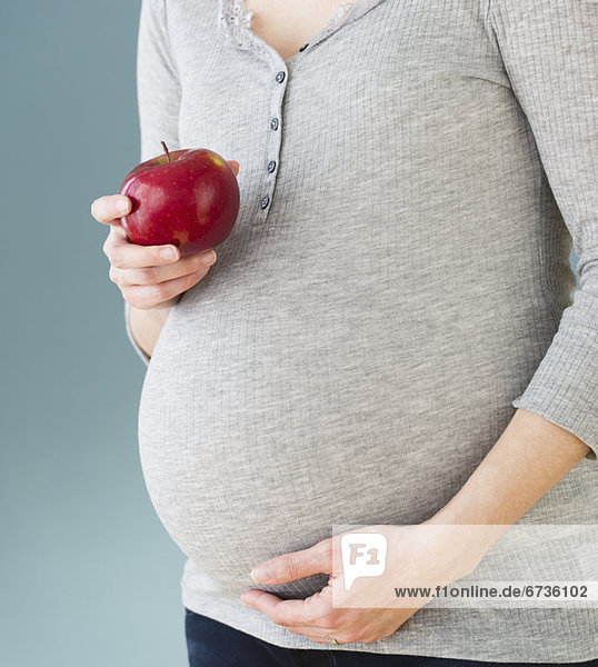 Frau  Mittlerer Ausschnitt  Schwangerschaft  Apfel  schießen  Studioaufnahme  essen  essend  isst