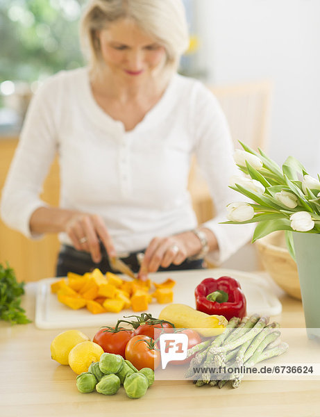 Portrait of senior woman cutting vegetables in kitchen