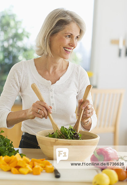 JPortrait of senior woman preparing salad in kitchen