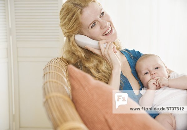Mother holding baby and talking on the phone