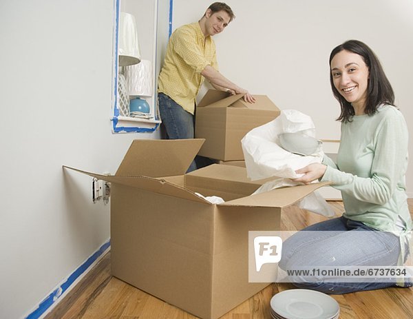 Couple unpacking boxes in new house