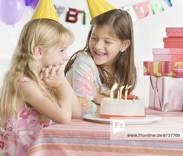 Young sisters with birthday cake at table