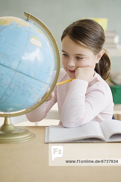 Mädchen Blick auf Globus im Klassenzimmer