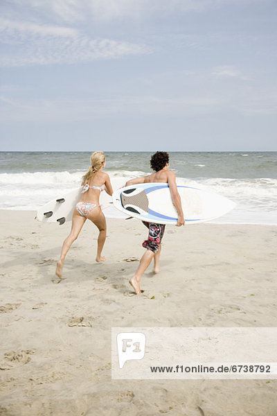 Couple running with surfboards