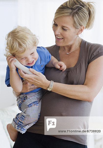 Pregnant mother holding child on telephone