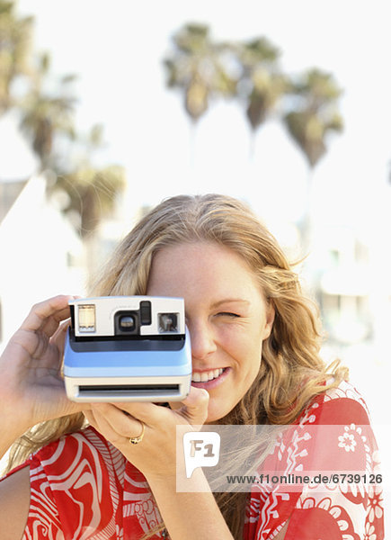 Woman taking photograph with instant camera