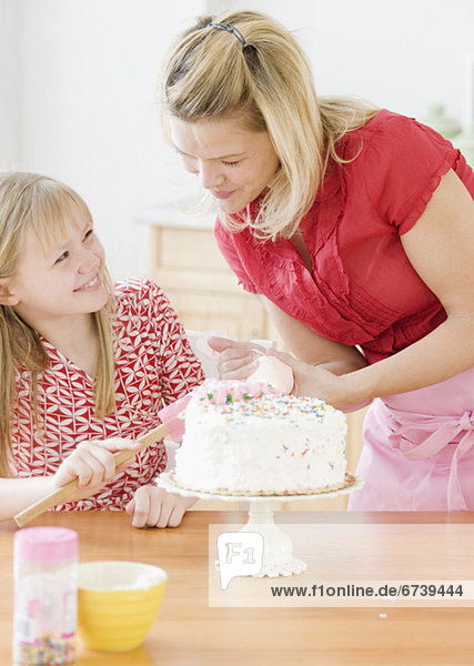Mother and daughter decorating birthday cake