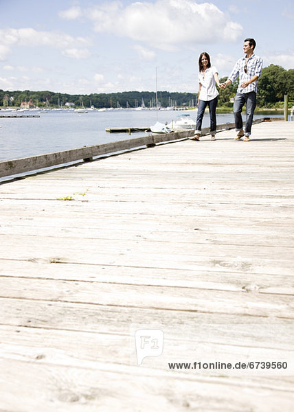 Couple holding hands and walking on dock