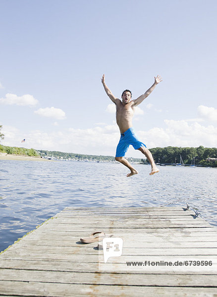 Portrait of man jumping off dock into lake