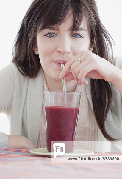 Portrait of young woman drinking fruit smoothie