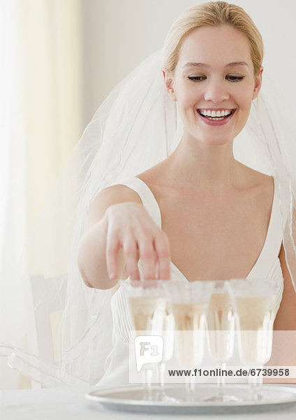 Young bride reaching for glass of champagne
