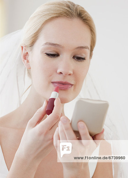 Young bride applying lipstick