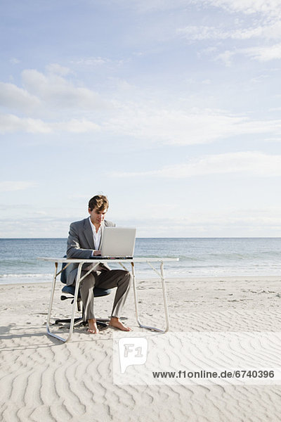 Businessman working at desk on the beach