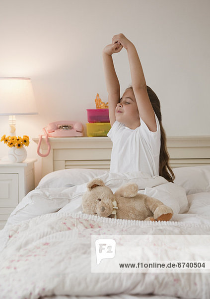 Young girl stretching in bed