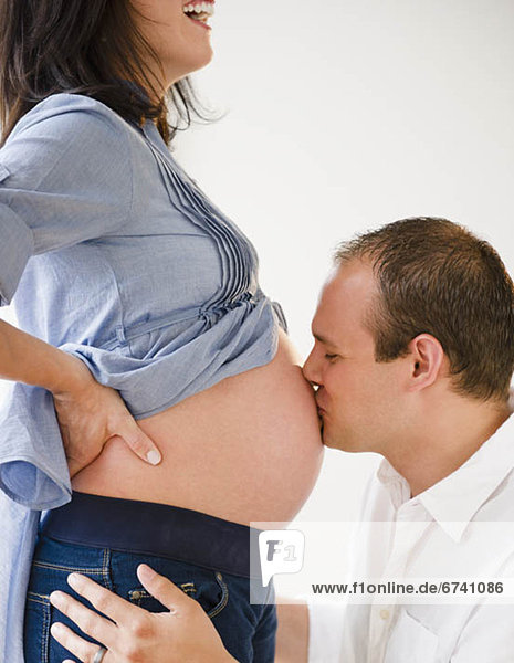 Young man kissing belly of pregnant woman