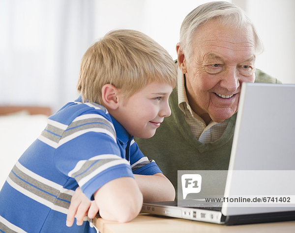 Grandfather and grandson (8-9) using laptop