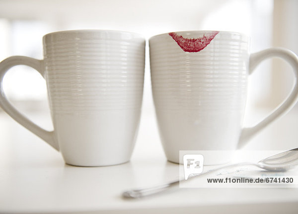 Close up of coffee mugs  one with red lipstick sign on edge