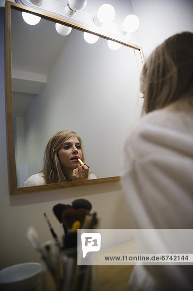 Reflection in mirror of woman doing make up