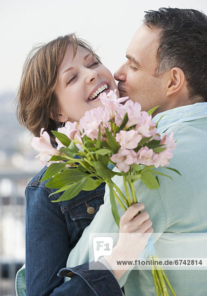 Couple embracing  woman holding flowers