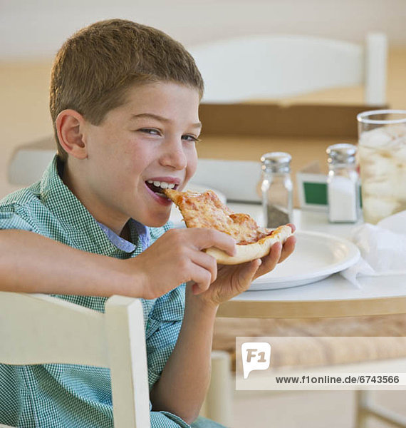 Boy (10-11) eating pizza