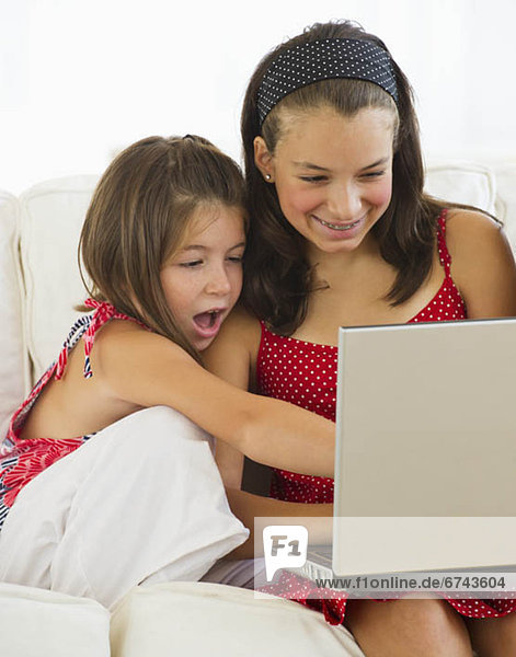 Sisters using laptop together (8-9 12-13)