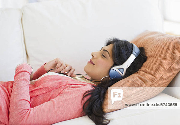 USA  New Jersey  Jersey City  Young attractive woman laying on back listening to music