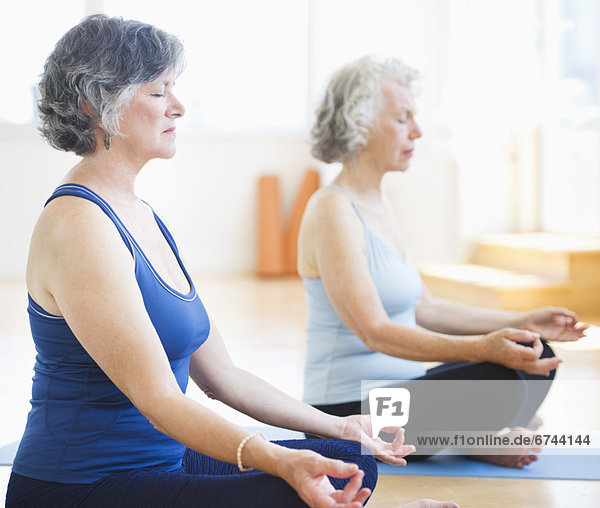 Two senior women practicing yoga