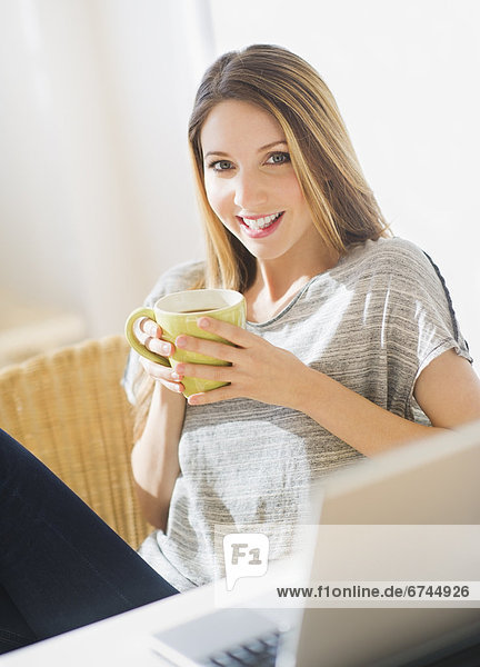 Portrait of young woman working with laptop and mug