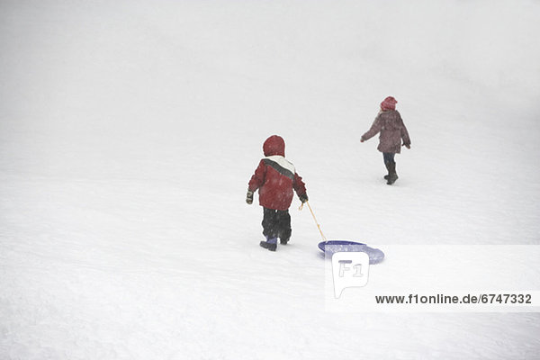 Kids pulling sled up snowy hill