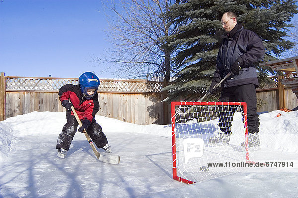 Father and Son Playing Hockey in Backyard