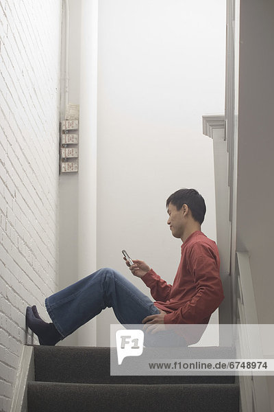 Man Sitting on Stairs Using Cell Phone