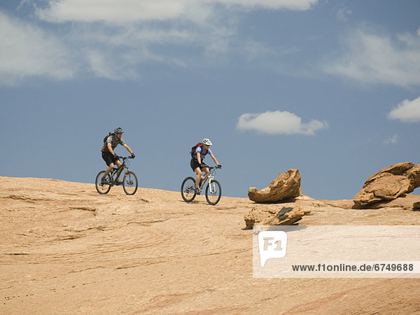 Couple riding mountain bikes in desert