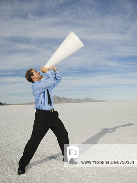 Businessman yelling into megaphone  Salt Flats  Utah  United States