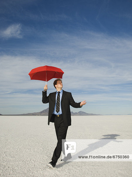 Businessman walking with umbrella  Salt Flats  Utah  United States