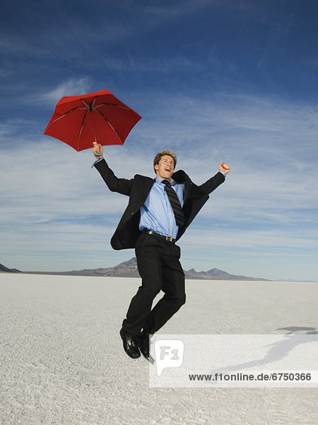 Businessman holding umbrella and jumping  Salt Flats  Utah  United States
