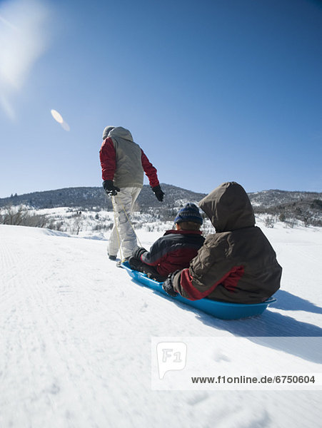 Father pulling children on sled