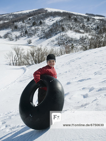 Boy carrying tube in snow