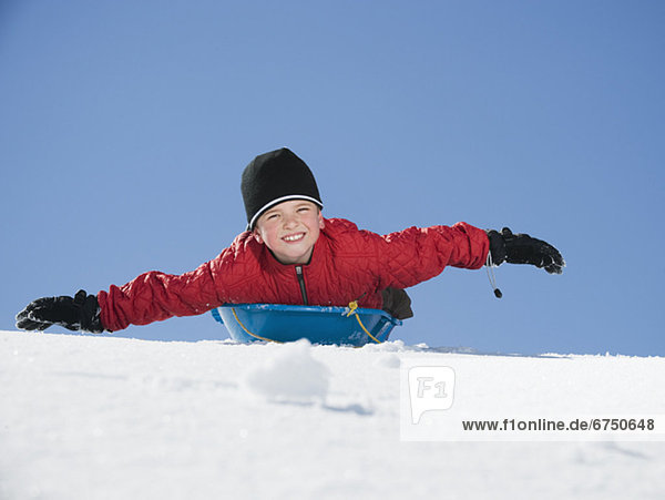Boy laying on sled in snow