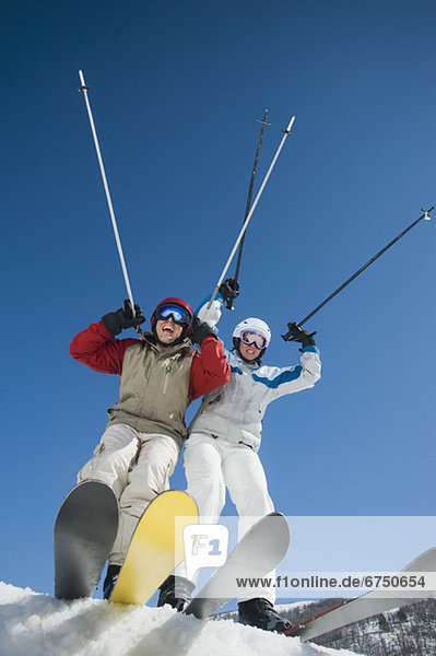 Couple with arms raised on skis