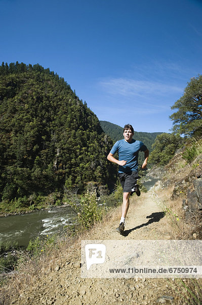 Man running on riverside trail