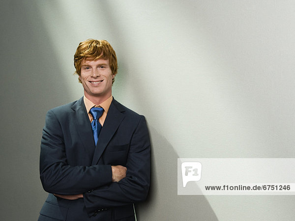 Confident businessman leaning against wall