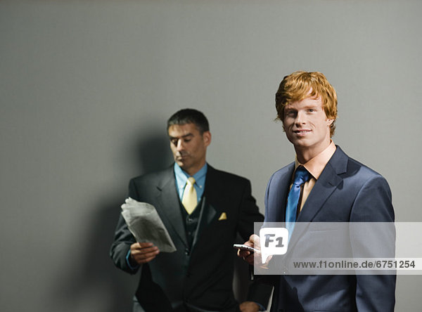 Businessmen holding newspaper and cell phone
