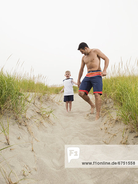 Father and son holding hands and running on beach